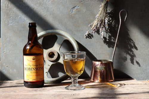 A bottle and glass of Robinsons Fine Dry Vintage Cider with a traditional cider jug